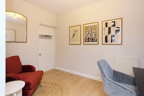 A room with a red sofa, a blue chair, and three framed artworks on the wall. - Belsize Park Scarlet Edit (London)