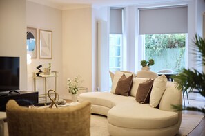 A living room with a sofa, a television, and a coffee table. - Belsize Park Scarlet Edit (London)