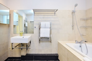 Un baño moderno con lavamanos blanco, toallero, ducha y espejo.
