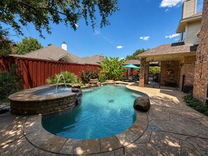 Un jardin avec une piscine, un jacuzzi et un espace patio.