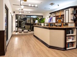 A modern reception area with a wooden floor, a reception desk, and a staircase leading to an upper level. - Hotiday Dormelletto Lago (Borgomanero)