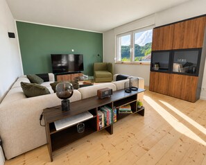 A modern living room with a sofa, a coffee table, a TV, and a bookshelf. - Holiday Home Eifelgluck - Castle View and Roof Terrace (Pelm)