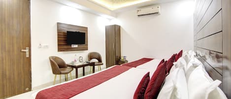 A hotel room with a bed, a TV, a desk, and chairs.