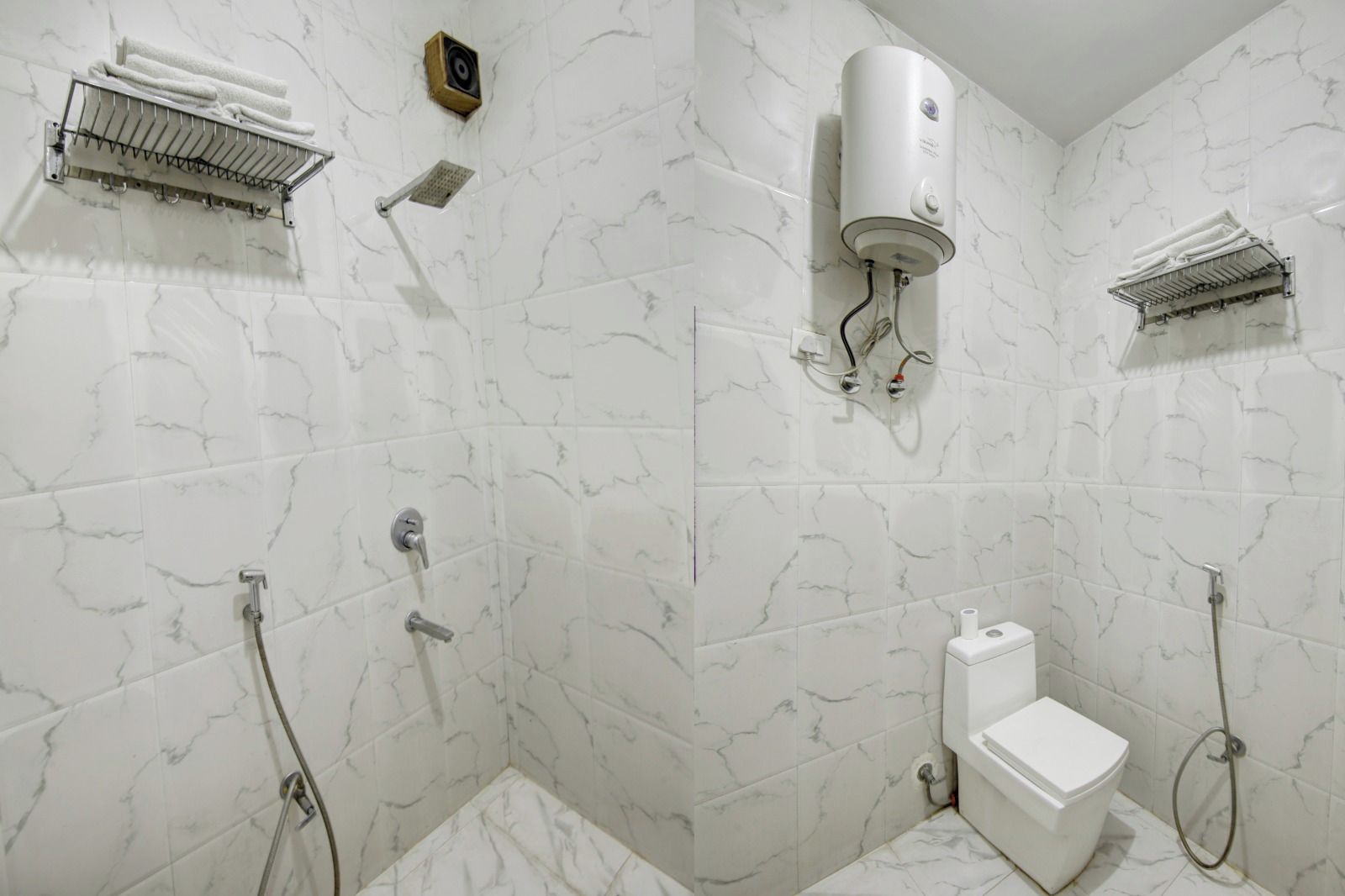 Une salle de bain équipée de toilettes, d’une douche et d’un porte-serviettes.