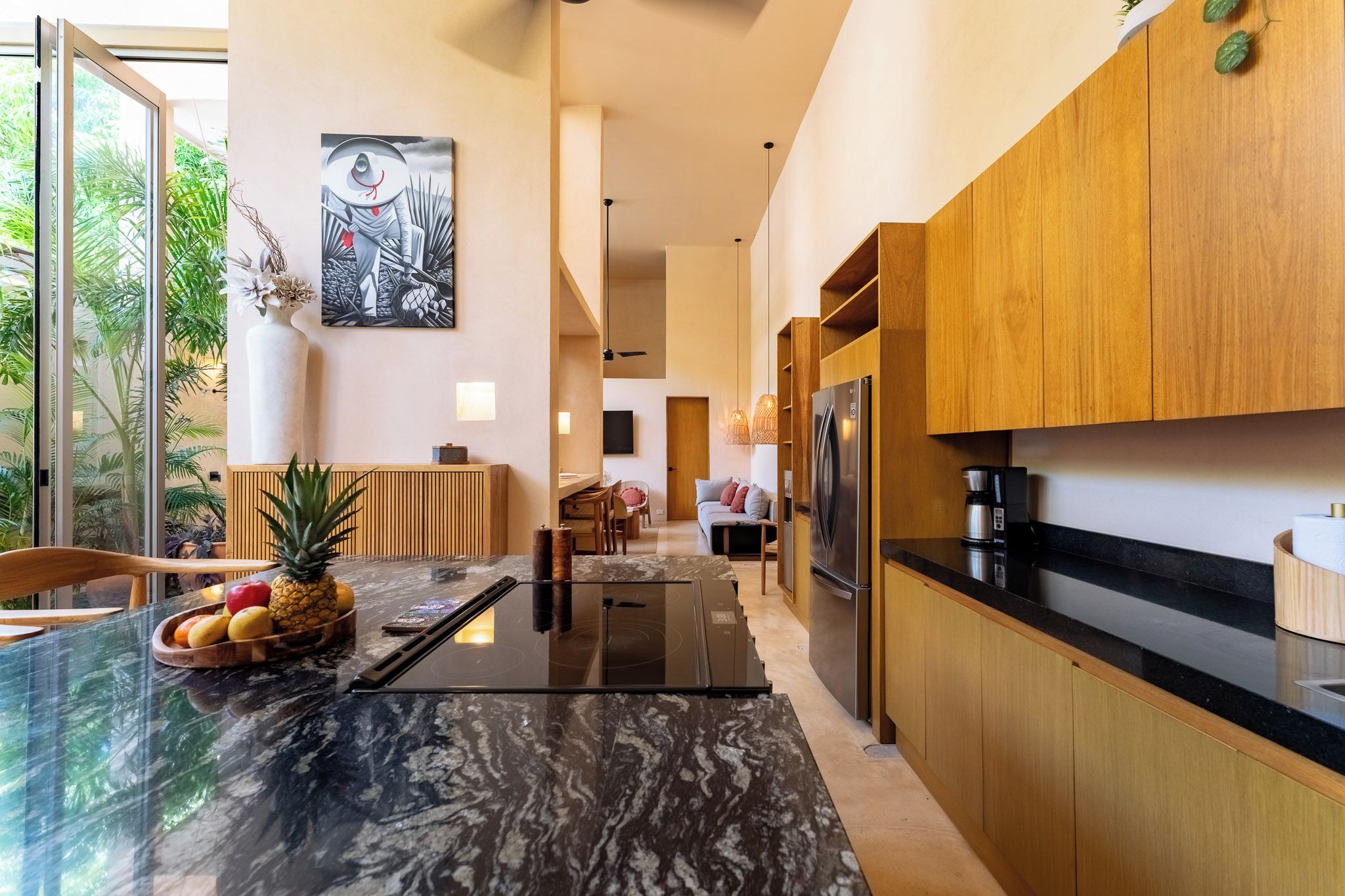 Een moderne keuken met een zwart marmeren aanrechtblad, houten kastjes en een roestvrijstalen koelkast.