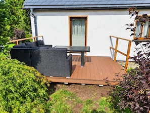 Eine Terrasse mit Gartenmöbeln, einem Tisch und einem Holzboden.