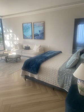 A modern bedroom with a large bed, a sofa, and two wall-mounted paintings. - Stunning 5 suite House with Swimming Pool and Lake (Armação dos Búzios)