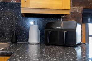 Eine Küche mit einem Toaster auf einer Granit-Arbeitsfläche, einem Papierhandtuchhalter und einer schwarzen Flasche.