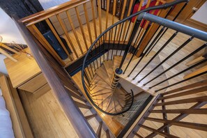 Eine Wendeltreppe mit Holzgeländern und einer Metallhandstange, die zu einer oberen Etage führt.