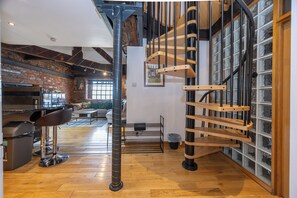 A modern interior with a wooden staircase, a bar area, and a brick wall. - Modern 2-BR Loft Flat W/Parking near Lime St (Liverpool)