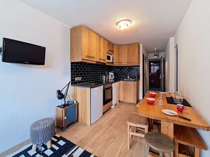 Eine kleine Küche mit Holzschränken, einer schwarzen Küchenzeile und einem Essbereich mit Holztisch und Stühlen.