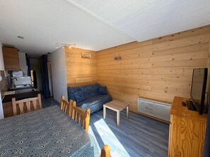A compact room with a kitchenette, a sofa, a dining table, and a small TV. - Cozy studio with slope view - 4 guests (Hauteluce)