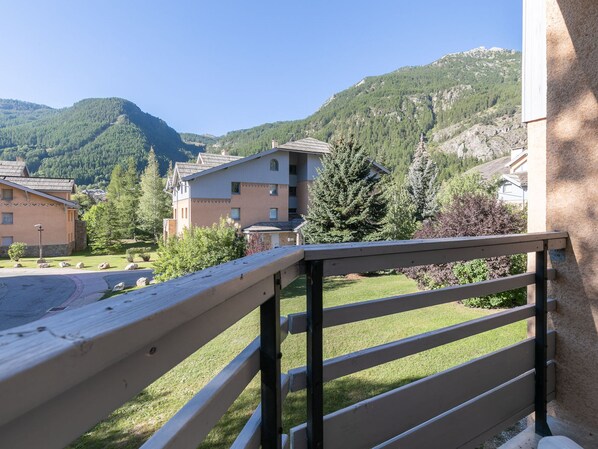 Un balcon donnant sur un quartier résidentiel, avec des maisons et une montagne en toile de fond.