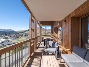 A wooden balcony with a table and chairs, overlooking a mountainous landscape. - Résidence Phoenix — Espace bien-être & salle de sport au cœur de la montagne (Huez)