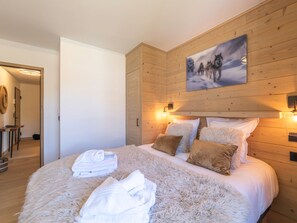 A bedroom with a wooden headboard, a painting of wolves, and a fluffy rug. - Résidence Phoenix — Espace bien-être & salle de sport au cœur de la montagne (Huez)