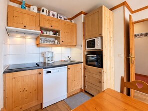 A compact kitchen with wooden cabinets, a dishwasher, a microwave, and a coffee maker. - Cosy apartment, pets allowed - 4 guests, mountain view (Notre-Dame-de-Bellecombe)
