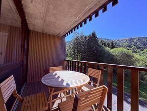 Eine Holzterrasse mit rundem Tisch und Stühlen mit Blick auf eine gebirgige Landschaft.