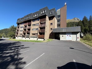 Ein mehrstöckiges Gebäude mit moderner Architektur, mit Balkonen und einem Parkplatz davor.