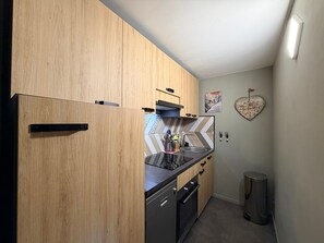 A compact kitchen with wooden cabinets, a built-in oven, and a sink. - Apartment with nature view - 4 guests (Mont-Dore)