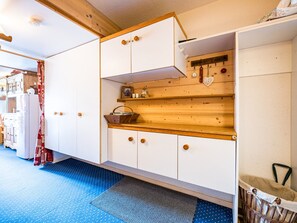 Een compacte keuken met houten kastjes, een inbouwkast en een blauw betegelde vloer.