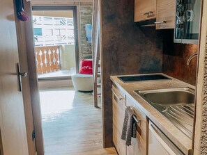 A kitchen with a built-in stove, a sink, and wooden cabinets. - Studio apartment at the foot of the slopes - 6 guests (Huez)