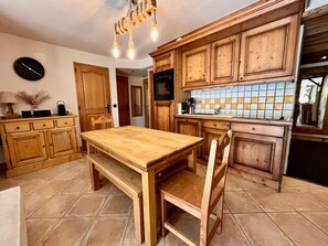 A kitchen with wooden cabinets, a wooden table, and a tiled backsplash. - Spacious apartment at the foot of the slopes - 6 guests (Morillon)