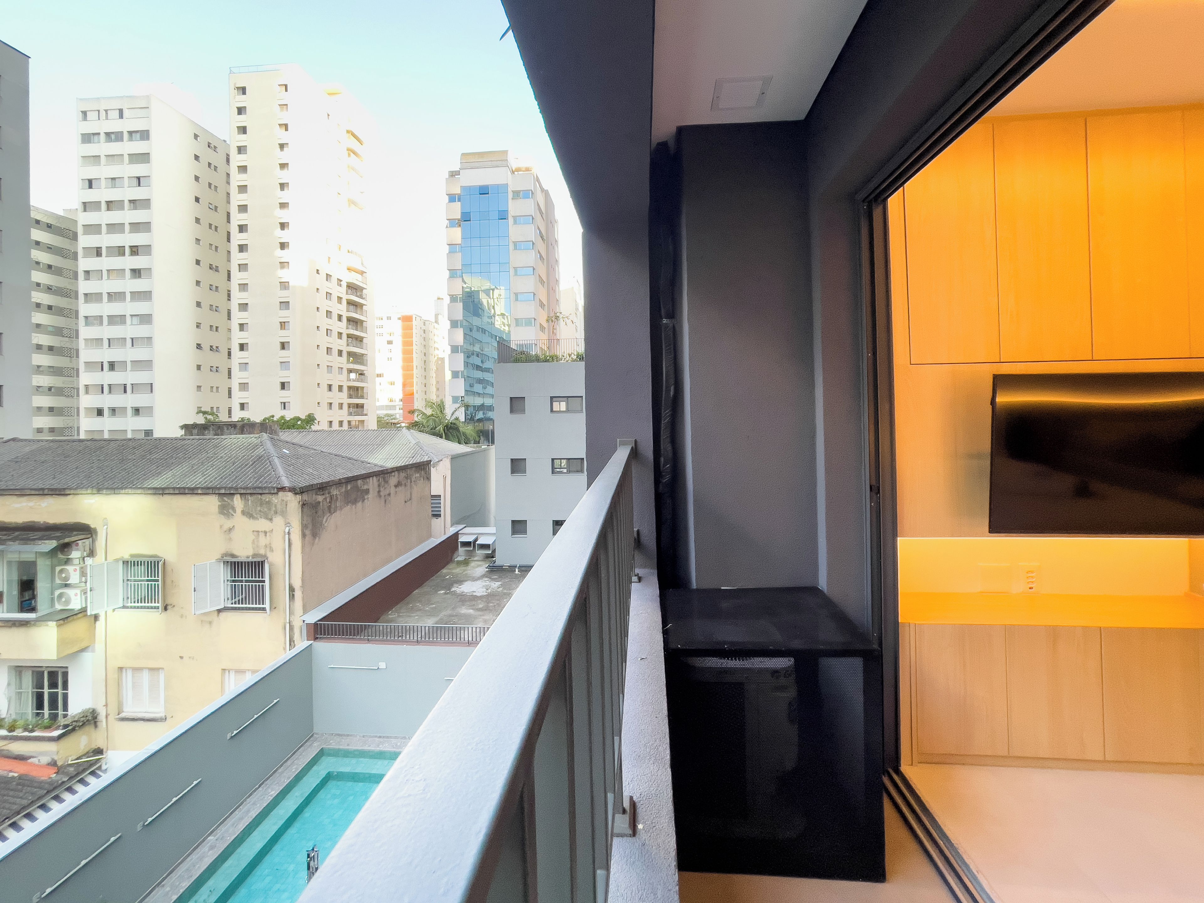 Uma varanda com piscina, vista de edifícios altos e área de cozinha moderna.