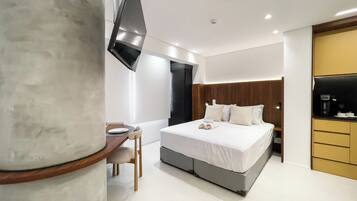 Quarto de hotel moderno com cama, mesa de cabeceira e televisão de tela plana na parede.