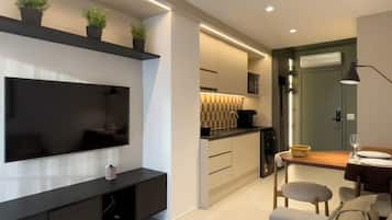 A modern living room with a flat-screen TV, a black entertainment unit, a sofa, and a dining area with a table and chairs.