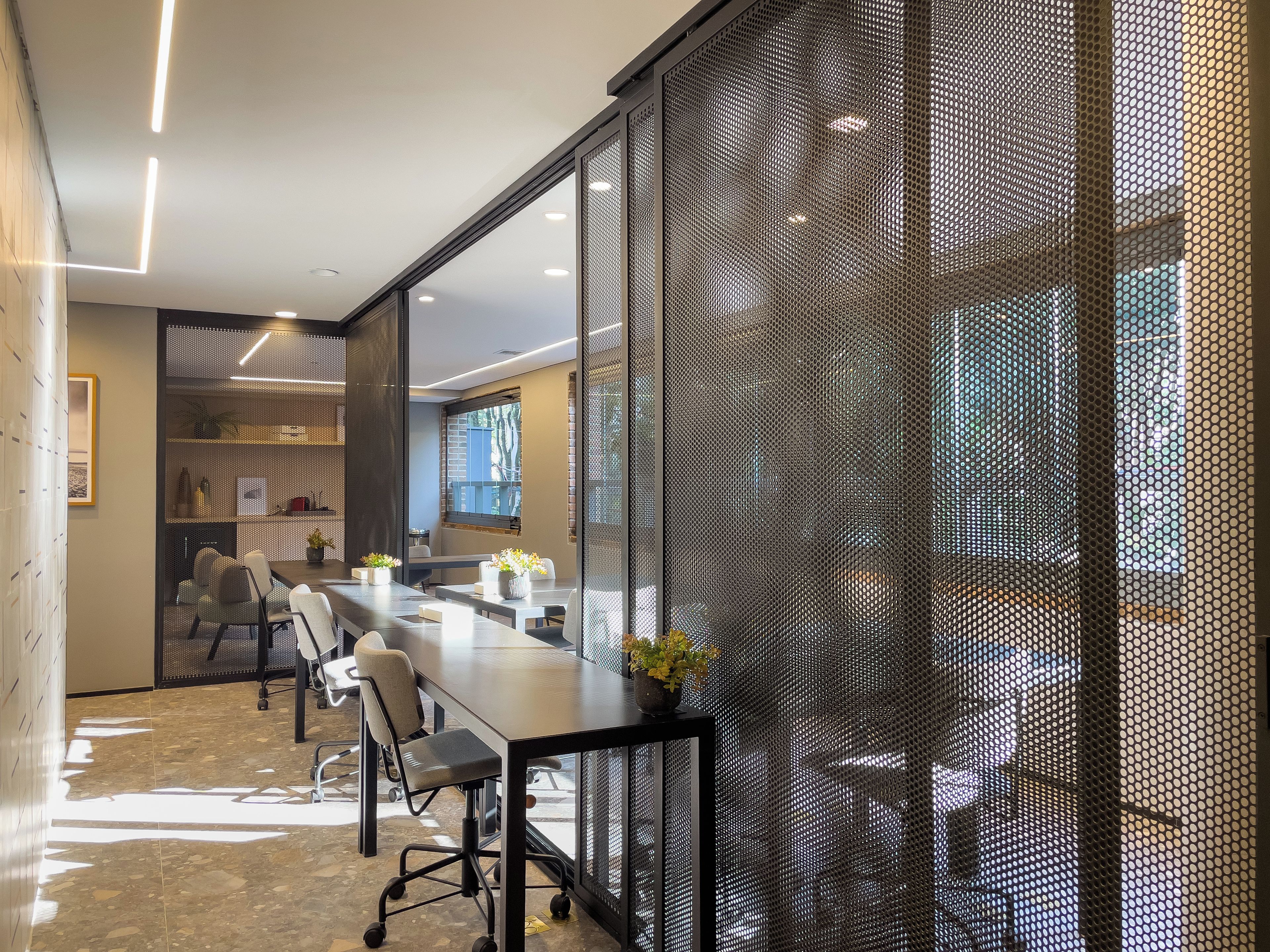A conference room with a long table, chairs, and a mesh partition.
