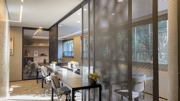 A conference room with a long table, chairs, and a mesh partition.