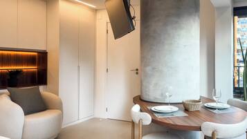 A modern interior with a dining area, a large pillar, and a television mounted on the wall.