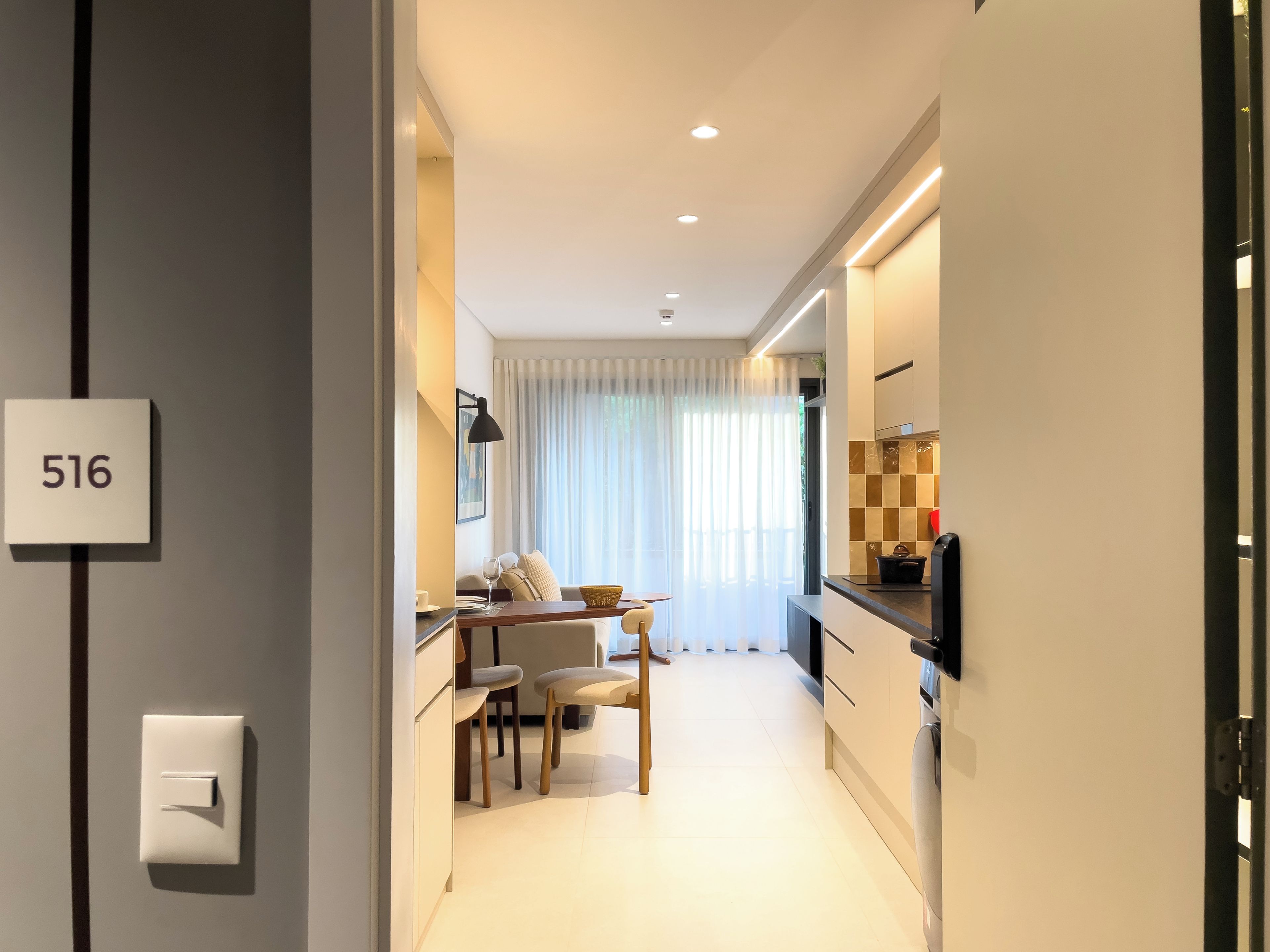 A modern kitchen with a dining area, a number sign '516' on the wall, and a visible light switch.
