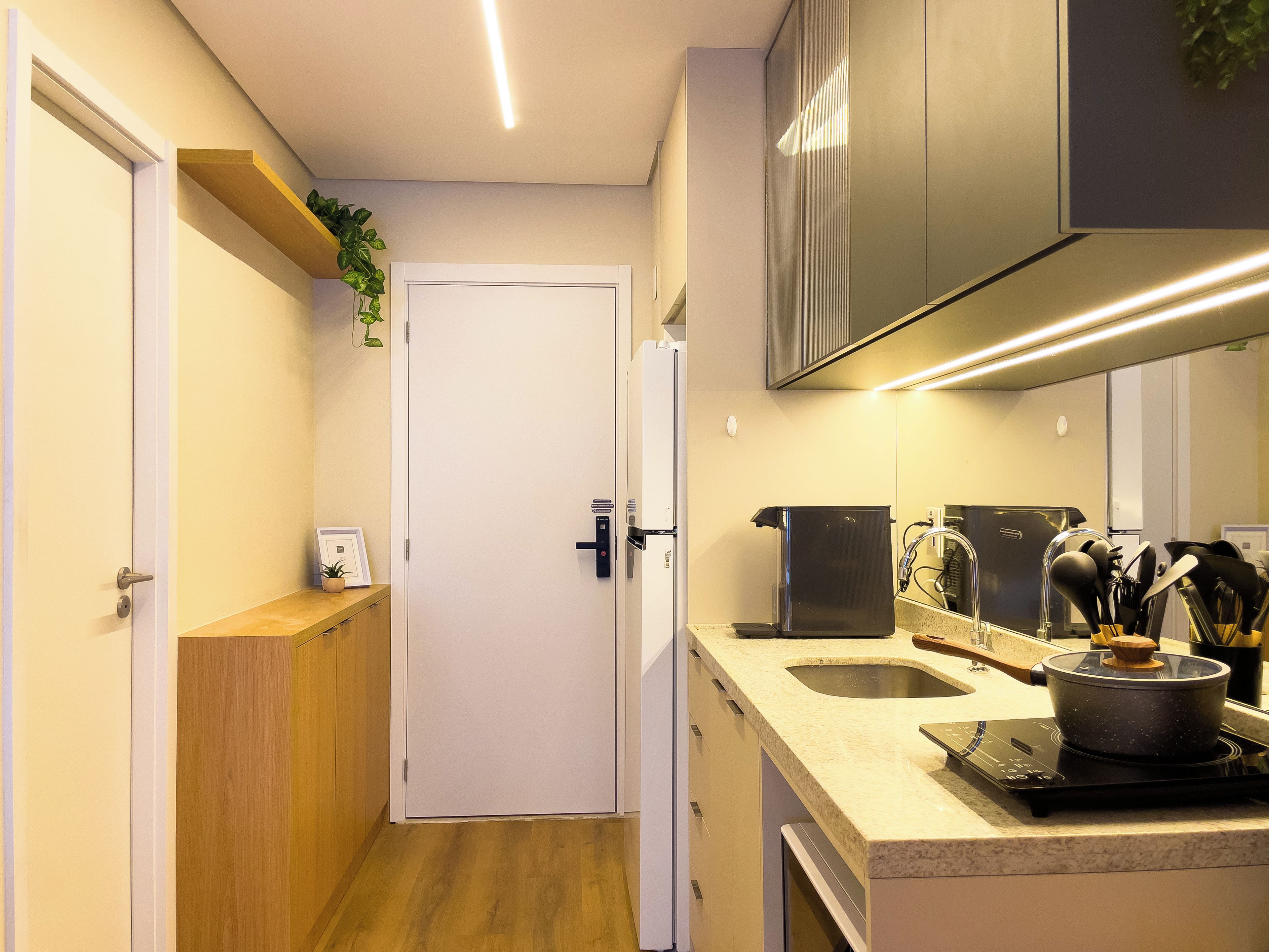A compact kitchen with a white door, wooden countertop, stainless steel appliances, and a built-in oven.