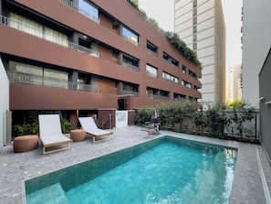 Un edificio moderno con piscina, poltrone a sdraio e una scala che conduce all'ingresso.