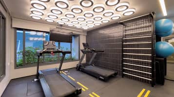 Ein Fitnessstudio mit Laufbändern, Fahrrädern und Trainingsbällen.
