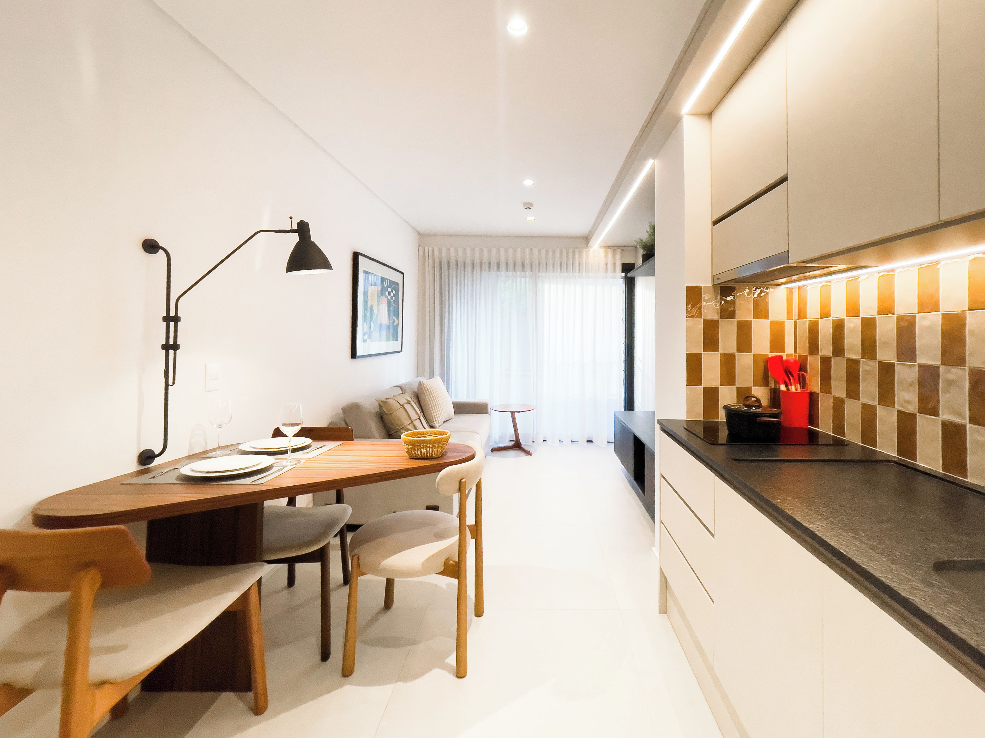A modern kitchen with a dining area, featuring a checkered backsplash, a dining table with chairs, and a sofa.