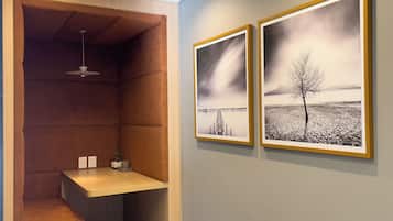 A room with a built-in bench, a small table, and two framed black and white landscape photographs on the wall.
