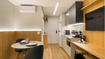A compact kitchen with a dining area, wooden paneling, a built-in oven, and a flat-screen TV.