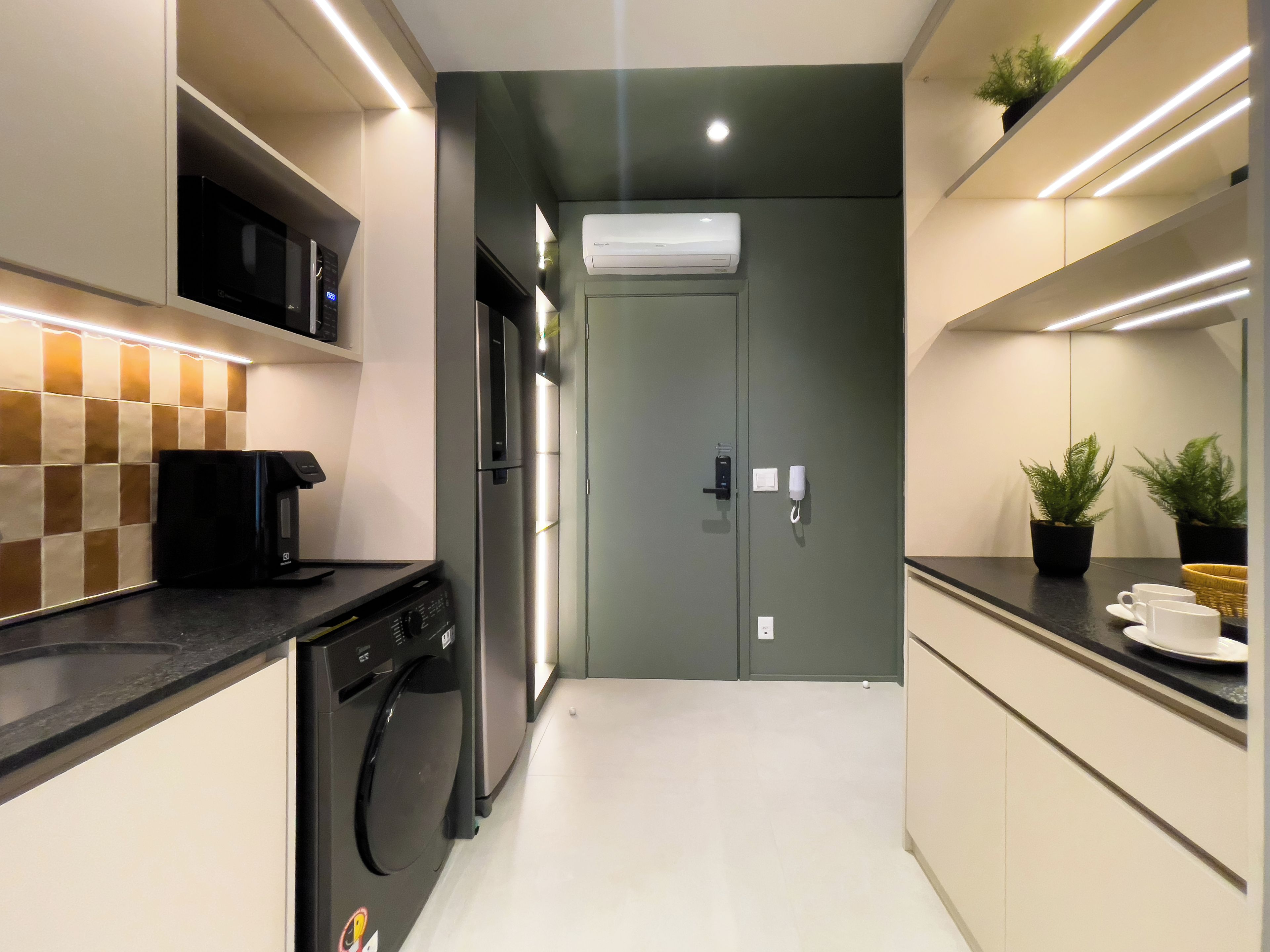 A modern kitchen with a dishwasher, microwave, and an air conditioning unit.