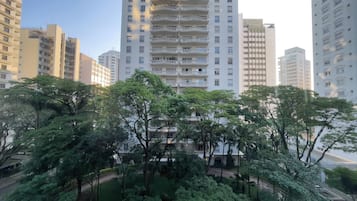 A high-rise building with multiple balconies and a surrounding green park area.
