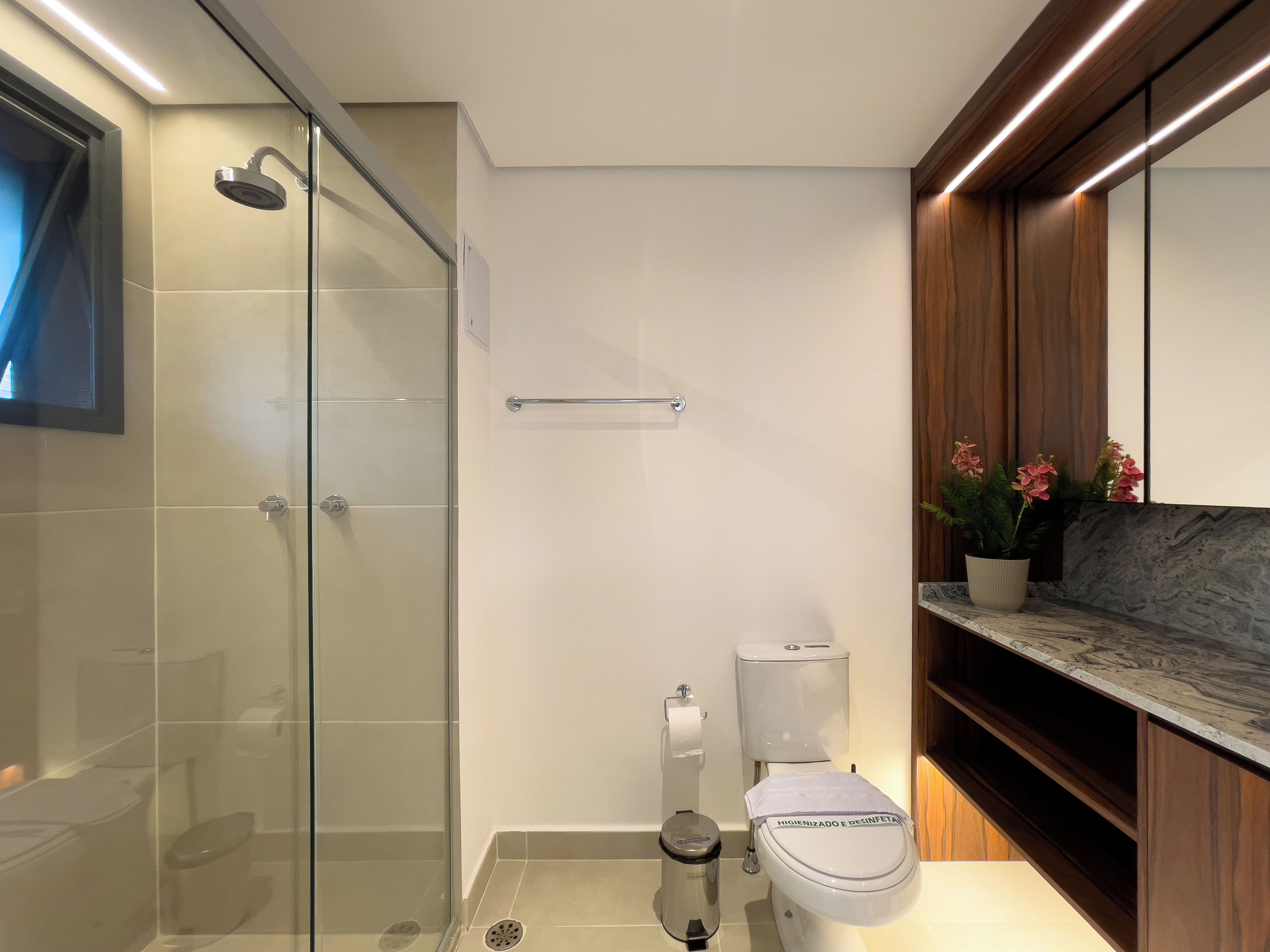 Un baño moderno con ducha envuelta en vidrio, inodoro y encimera de mármol.