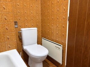 A bathroom with a white toilet, a radiator, and patterned tiles. - Apartment in Méribel center - 4 guests (Les Allues)