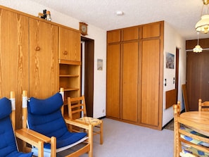 A room with wooden furniture, including a chair, a table, and a wardrobe. - Apartment in Méribel center - 4 guests (Les Allues)