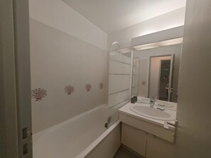 A bathroom with a bathtub, a sink, and a mirror. - Air-conditioned apartment near beach (Saint-Cyprien)