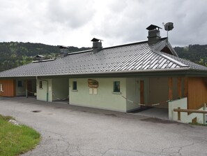 Ein Gebäude mit einer Metallbedachung, einer Schilder mit der Aufschrift 'Chalet Les Bourneaux' und einem Zaun aus Maschendraht davor.
