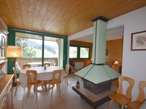 Ein Essbereich mit Holzbalkendecke, einem Tisch mit Stühlen und einem Kamin.