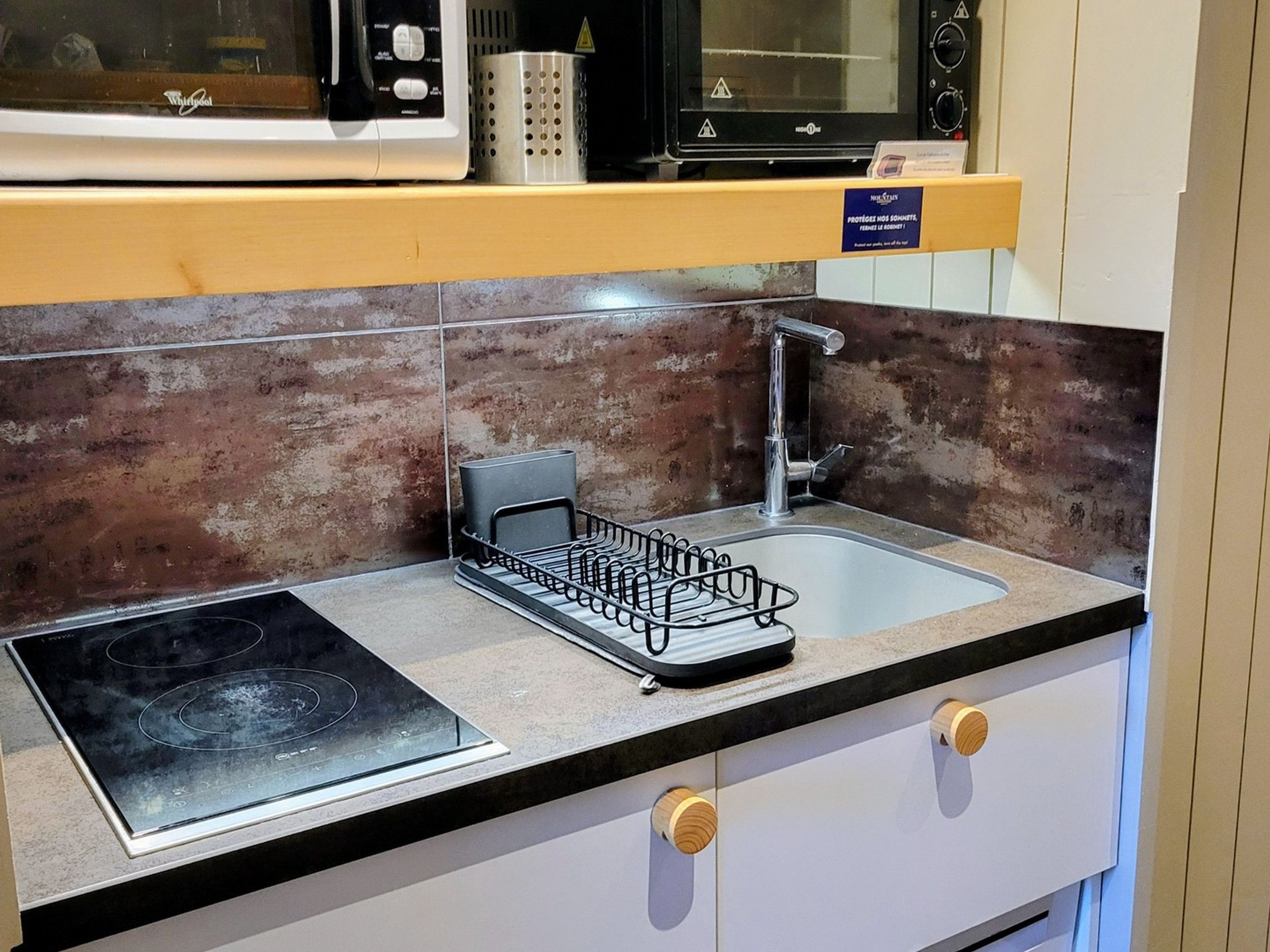 A kitchen with a built-in stove, a sink, and a microwave above the counter.
