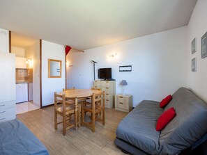 Ein gemütlicher Wohnbereich mit Essplatz, einer Couch, einem Fernseher und einer Küchenzeile.