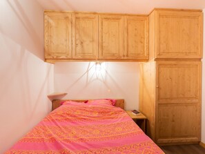 Ein Schlafzimmer mit einem Bett, einem Holzschrank und einem Nachttisch mit einem Buch.